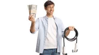 A man holds an electric vehicle charging cable in one hand and a fanned-out stack of cash in the other.